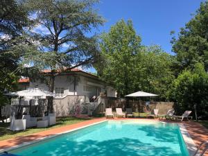 uma piscina com cadeiras e guarda-sóis em frente a uma casa em Villa Barbara em Santa Luce