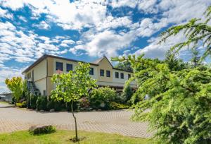 una casa bianca con degli alberi di fronte di Pension zum Reiterhof a Schmogrow