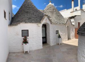 a white building with a roof with two potted plants at Trulli Family - Trulli&Cummerse in Alberobello
