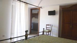 a bedroom with a bed and a chair and a window at Trulli e Cummerse in Locorotondo