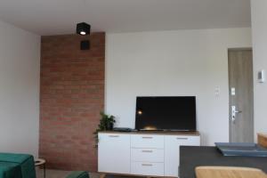 uma sala de estar com uma televisão de ecrã plano numa parede de tijolos em Apartament Kliwia em Tolkmicko
