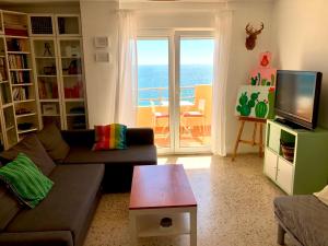 ein Wohnzimmer mit einem Sofa, einem TV und einem Balkon in der Unterkunft GATU Villa Bani con terraza y vista frontal al mar in Cádiz