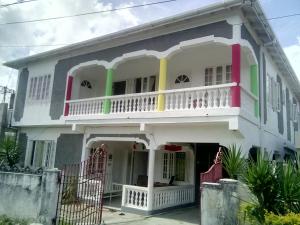uma grande casa branca com uma varanda em Porty Hostel em Port Antonio
