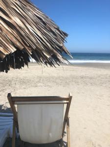 ein Sonnenschirm und ein Stuhl am Strand in der Unterkunft Los Cocos de Vichayito in Vichayito