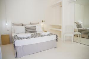 a white bedroom with a bed and a mirror at Dimora Ausentum in Torre San Giovanni Ugento