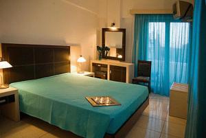 a bedroom with a large bed with a blue blanket at Hotel Afea in Agia Marina Aegina