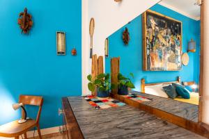 Boipeba Guesthouse في ألغيرو: غرفة بجدران زرقاء وطاولة وسرير