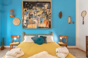 Boipeba Guesthouse في ألغيرو: غرفة نوم بسرير اصفر بجدار ازرق