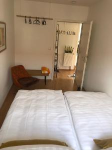 a bedroom with a white bed and a chair at Zentraler geht es kaum - in königlicher Nachbarschaft! in Ludwigsburg