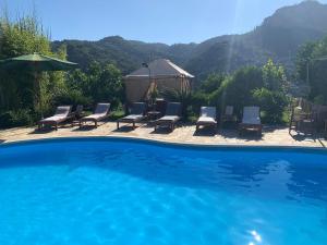 a swimming pool with chairs and umbrellas in a yard at La Beverita in Ventimiglia