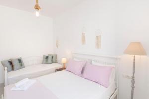 a white bedroom with two beds and a lamp at Arsis Houses, Big House in Antiparos