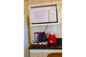 un microondas en un estante sobre un mostrador de cocina en Apartamento novo, completo e com ótima localização, en Pirassununga