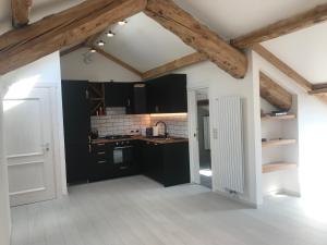kuchnia z czarnymi szafkami i drewnianym sufitem w obiekcie The Bijoux - Dolomites w mieście Agordo