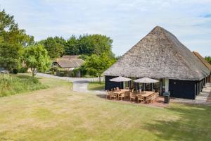 un edificio con techo de paja con mesas y sombrillas en Great Higham Barn Complex by Bloom Stays, en Canterbury