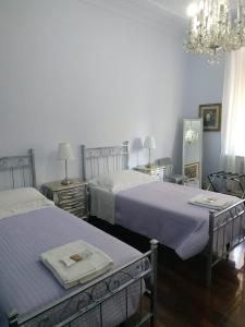 a bedroom with two beds and a chandelier at Around The Corner Colosseo B&B in Rome