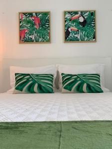 a bed with two pillows and two paintings on the wall at Belém Lodge in Ponta Delgada