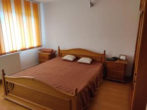 1 dormitorio con cama de madera y 2 almohadas en Cazare Buzău, en Buzau