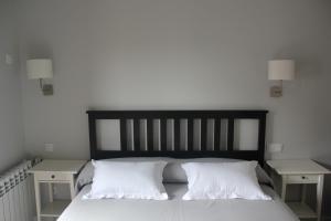 a bed with white pillows and two night stands at Casa Rural La Calzada in El Payo +38 photos