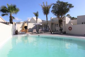 una piscina frente a una casa con palmeras en Villa Sol Suite, en Los Pocillos