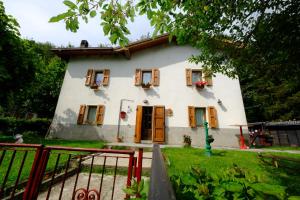 Cette petite maison blanche est dotée de portes et de fenêtres marron. dans l'établissement B&B La Tana Dei Ricci, à Sestola