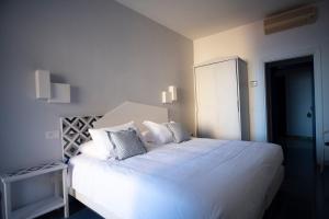 a white bedroom with a large white bed with pillows at Hotel Baia Di Puolo in Massa Lubrense