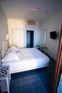 a large white bed in a room with a tv at Hotel Baia Di Puolo in Massa Lubrense