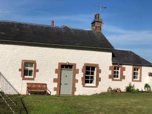 a white house with a bench in front of it at Laundry Cottage in Dumfries