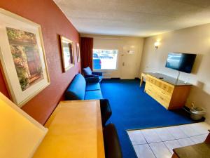 een hotelkamer met een bank en een televisie bij Breeze Inn & Suites, Virginia Beach in Virginia Beach