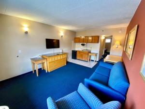 een woonkamer met een blauwe bank en een televisie bij Breeze Inn & Suites, Virginia Beach in Virginia Beach