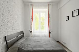 a bed in a white room with a window at Apartament w centrum :) in Krakow