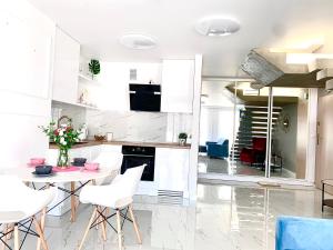 a kitchen with white cabinets and a table and chairs at Apartament Bursztynek Jantar Park in Jantar