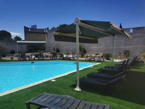 una piscina con sillas, una sombrilla y una piscina en Hôtel Le Floreal en Trèbes