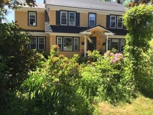 uma casa amarela com um ramo de flores no quintal em The Stella Rose B&B em Wolfville