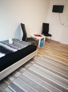 a bedroom with a bed and two chairs and a rug at Pension Forstfeld Kassel in Kassel