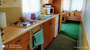a kitchen with a stove top oven next to a sink at Gina's Static caravan,118 Sandsgate in Hemsby
