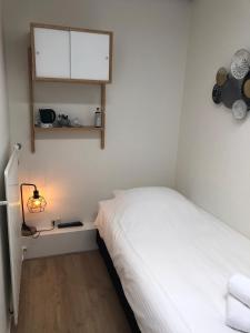 a small bedroom with a white bed and a window at Hotel-Brasserie De Walvisvaarder in Hollum