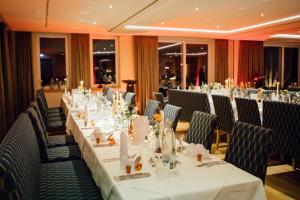 een lange tafel met witte tafels en stoelen in een restaurant bij Alte Mühle Hotel & Restaurant in Rödental