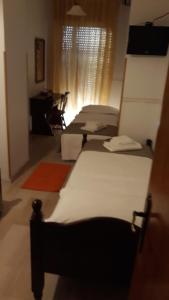 szereg łóżek w pokoju z biurkiem w obiekcie Locanda Ermes w Capaccio-Paestum