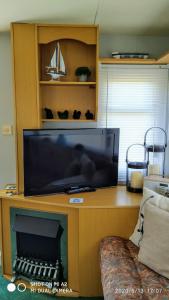 a large flat screen tv sitting on a entertainment center at Gina's Static caravan,118 Sandsgate in Hemsby