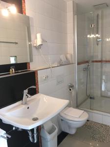 ein Bad mit einem Waschbecken, einem WC und einer Dusche in der Unterkunft Landhotel Steffen in Lieser