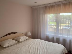 sypialnia z białym łóżkiem i oknem w obiekcie Apartamenti Bulvāris w mieście Alūksne