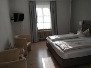 ein Schlafzimmer mit einem Bett, einem Stuhl und einem Fenster in der Unterkunft Landhotel Steffen in Lieser