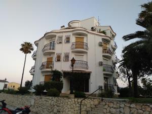 a white building with balconies and palm trees at Estudio Caballo-Piscina in Denia