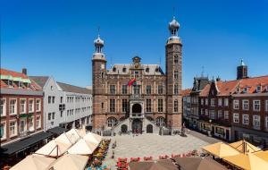an old building with a clock tower in a city at Theaterhotel Venlo in Venlo