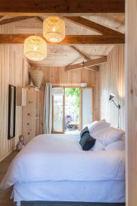 a large white bed in a room with wooden walls at Centre Cap-ferret, les chambres du phare, bassin in Cap-Ferret