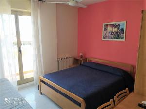 um quarto com uma cama azul e uma parede vermelha em Hotel Eliseo em Giardini Naxos