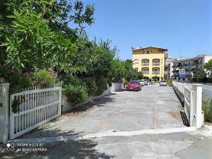 uma rua com uma cerca branca e um carro vermelho em Hotel Eliseo em Giardini Naxos