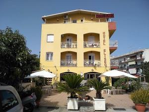 un bâtiment jaune avec des parapluies devant lui dans l'établissement Hotel Eliseo, à Giardini Naxos