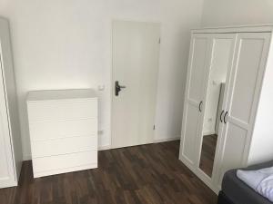 ein weißes Schlafzimmer mit einer Tür und einem Spiegel in der Unterkunft Ferienwohnung An der Gildenstr. 2 in Borken