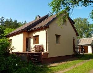 una piccola casa bianca con portico e tavolo di Lakefront house in Senoji Varėna a Varėna